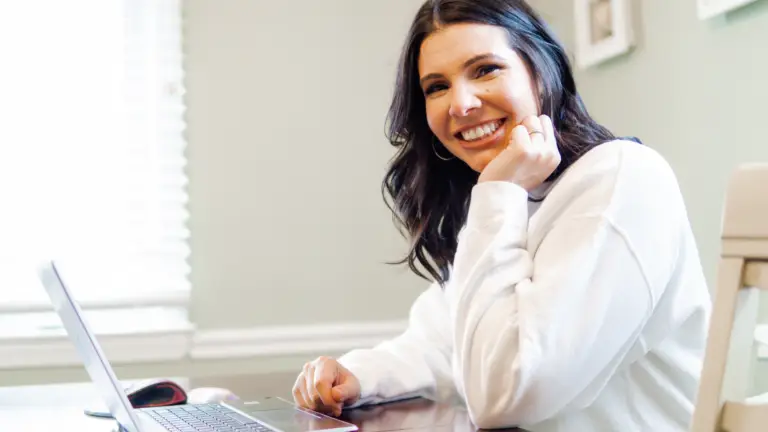 smiling woman at table with computer